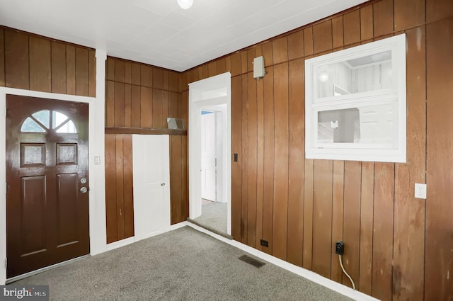 carpeted entryway with wooden walls