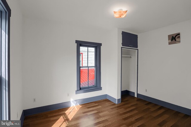 unfurnished bedroom featuring a closet and dark hardwood / wood-style floors