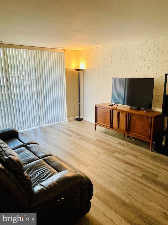 living room featuring brick wall and light hardwood / wood-style flooring