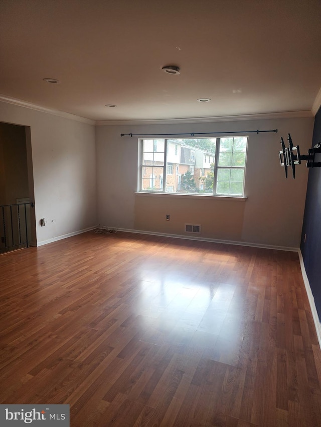 unfurnished room with baseboards, visible vents, crown molding, and wood finished floors