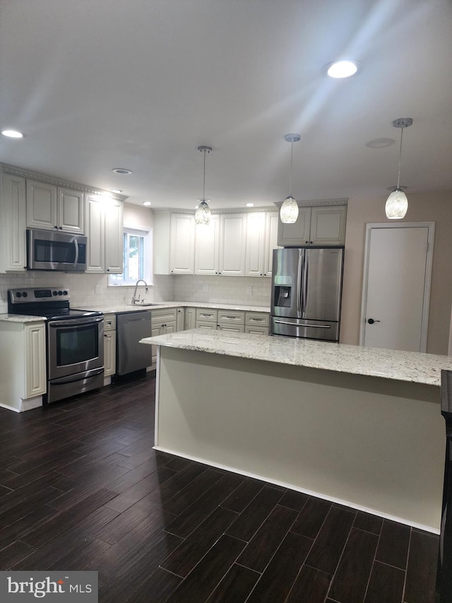 kitchen featuring appliances with stainless steel finishes, sink, dark wood-type flooring, and hanging light fixtures