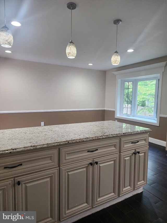 kitchen with hanging light fixtures, light stone counters, and dark hardwood / wood-style flooring