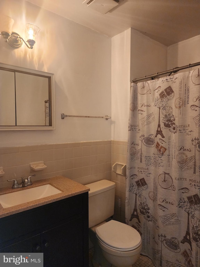 bathroom featuring vanity, backsplash, walk in shower, tile walls, and toilet