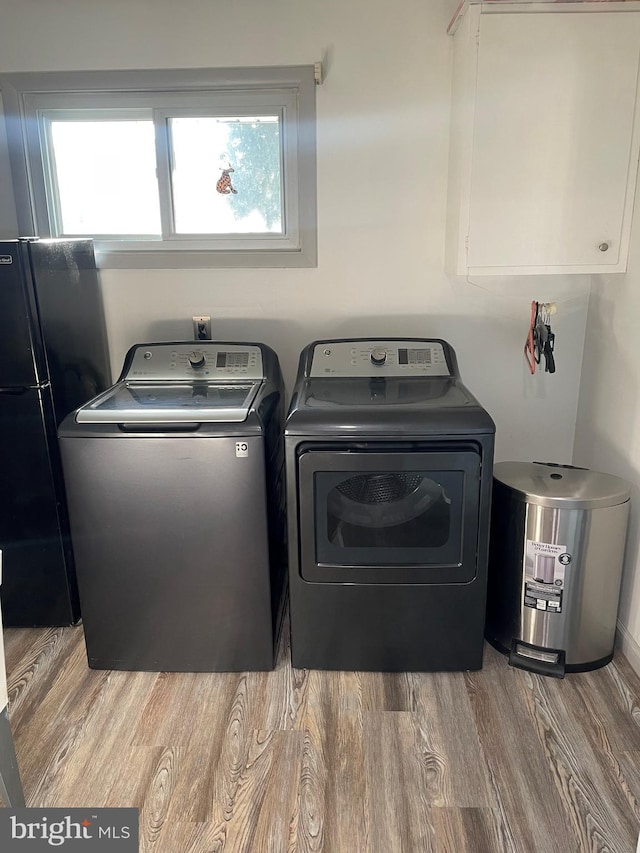 laundry area with light wood-type flooring, washing machine and clothes dryer, and plenty of natural light