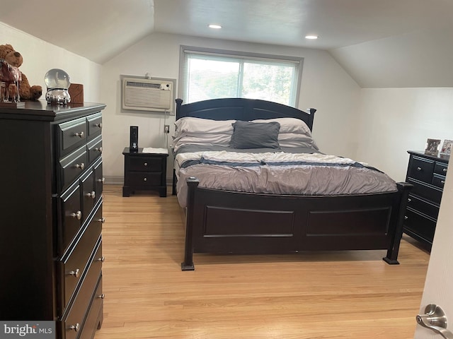 bedroom with light wood-type flooring, lofted ceiling, and a wall mounted air conditioner