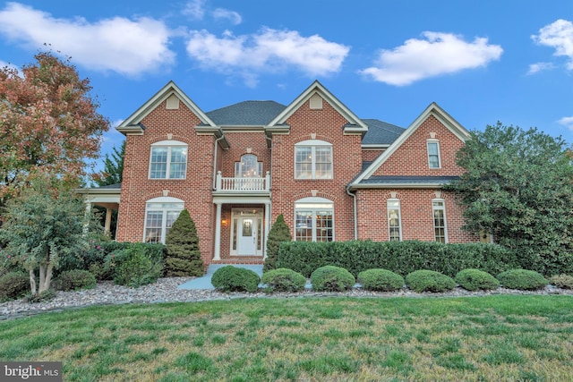 view of front facade with a front lawn and a balcony