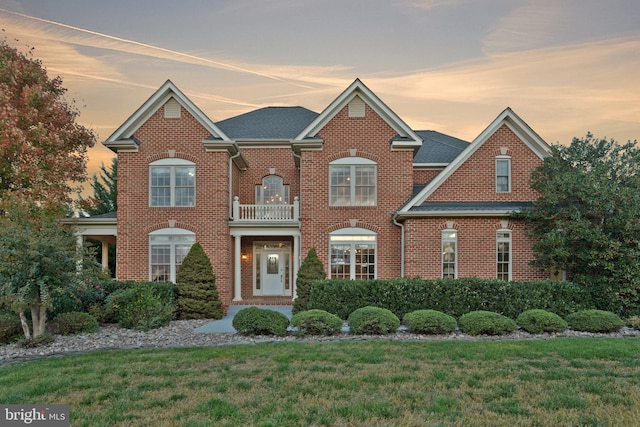 view of front of home with a yard and a balcony