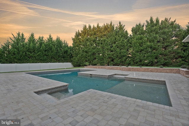 pool at dusk with a patio area