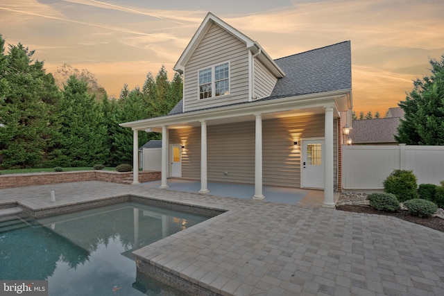 pool at dusk featuring a patio