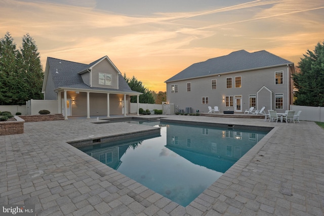 pool at dusk featuring a patio