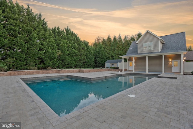 pool at dusk with a patio area