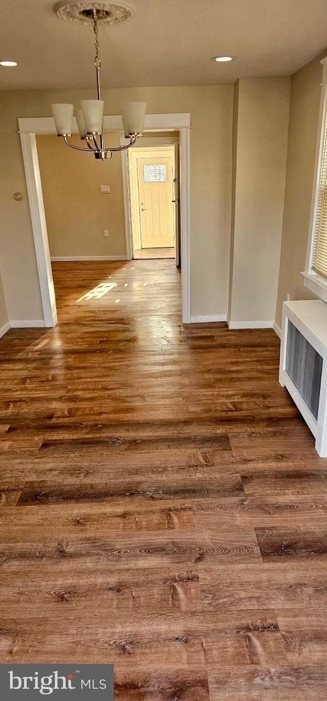 unfurnished dining area featuring wood finished floors, baseboards, and a chandelier