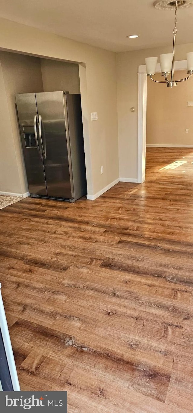 interior space featuring pendant lighting, wood finished floors, stainless steel fridge, baseboards, and a chandelier