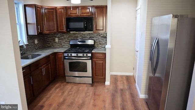 kitchen with a sink, stainless steel appliances, tasteful backsplash, and wood finished floors