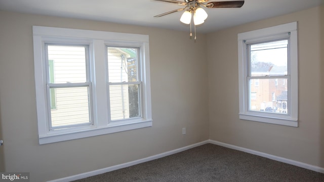 empty room featuring a ceiling fan, baseboards, and dark colored carpet