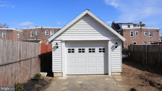 detached garage featuring driveway and fence