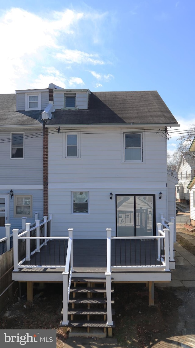 rear view of house with a deck and roof with shingles