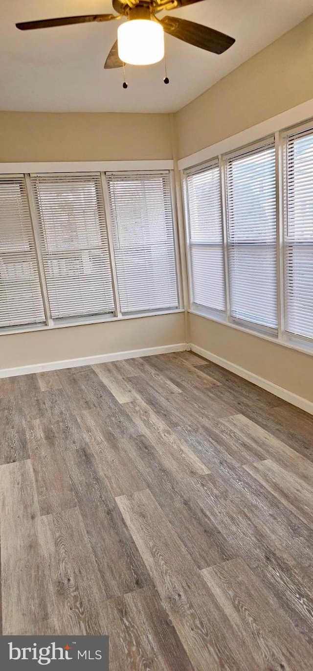 spare room with baseboards, a ceiling fan, and wood finished floors