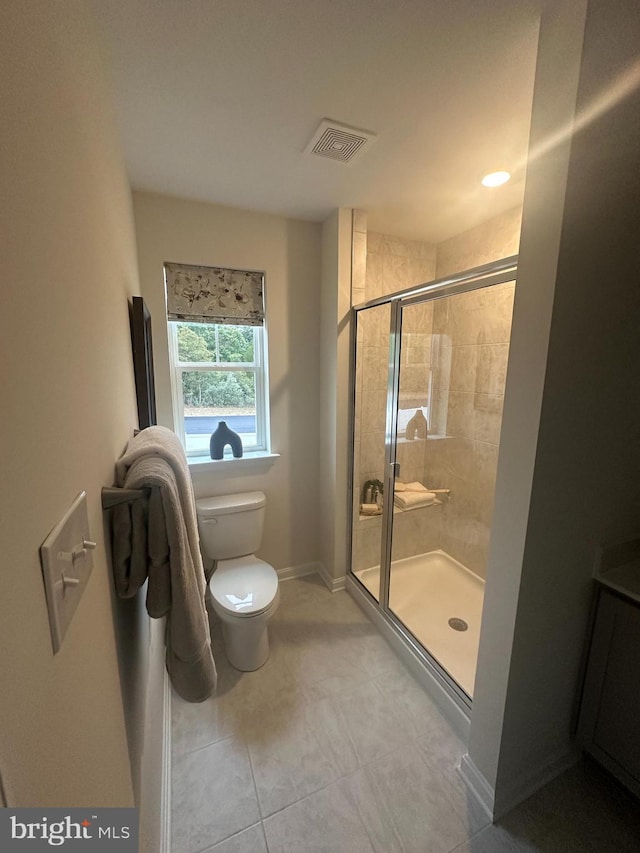 bathroom featuring tile patterned flooring, toilet, and walk in shower