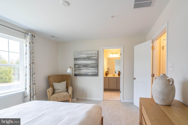 bedroom featuring ensuite bathroom and light colored carpet