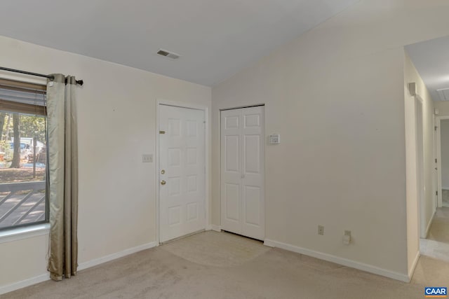 unfurnished bedroom featuring vaulted ceiling and light colored carpet