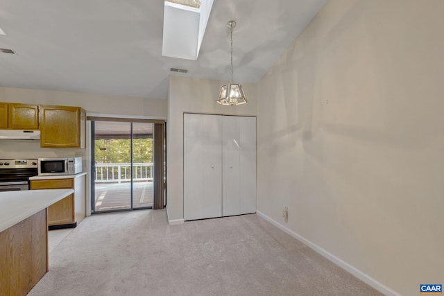 kitchen with a skylight, decorative light fixtures, appliances with stainless steel finishes, a chandelier, and light carpet