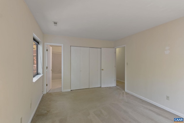 unfurnished bedroom with light carpet and a closet