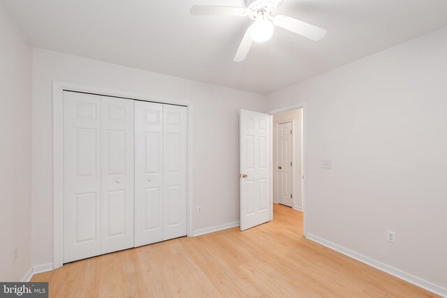 unfurnished bedroom featuring ceiling fan, a closet, and light wood-type flooring