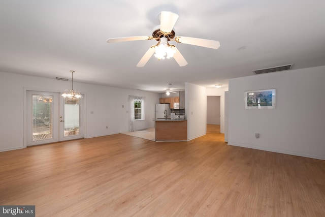 unfurnished living room with ceiling fan with notable chandelier, french doors, and light hardwood / wood-style flooring