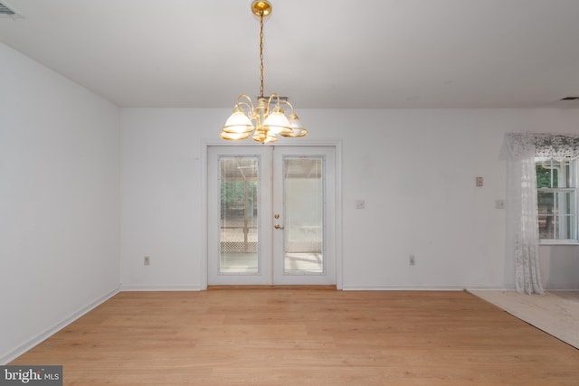 unfurnished dining area with a notable chandelier, light hardwood / wood-style flooring, french doors, and a healthy amount of sunlight