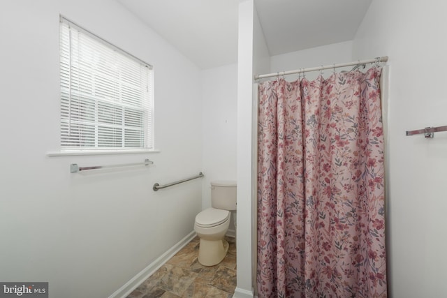 bathroom featuring toilet, curtained shower, and tile patterned flooring