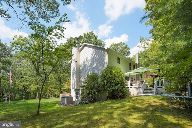 view of property exterior featuring a lawn, a wooden deck, and cooling unit