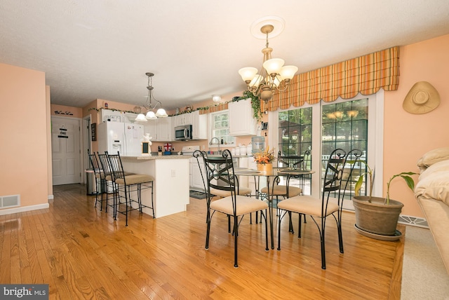 dining area with an inviting chandelier and light hardwood / wood-style flooring