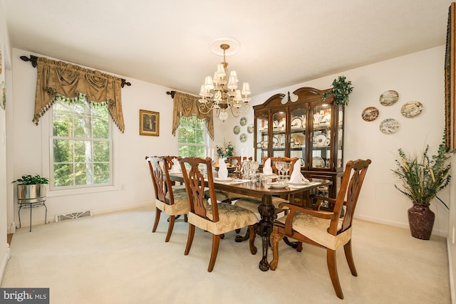 dining room with light carpet and a chandelier