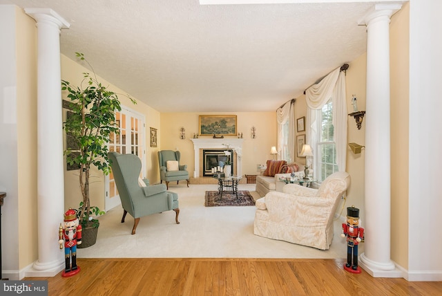 living room featuring a textured ceiling, hardwood / wood-style floors, and decorative columns