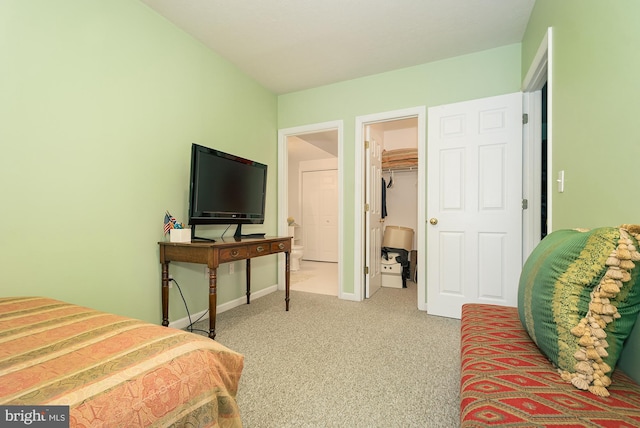 bedroom featuring a walk in closet, light colored carpet, and a closet