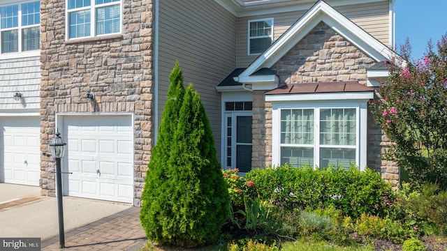 view of side of home featuring a garage and stone siding