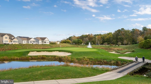 view of home's community featuring view of golf course, a water view, and a yard