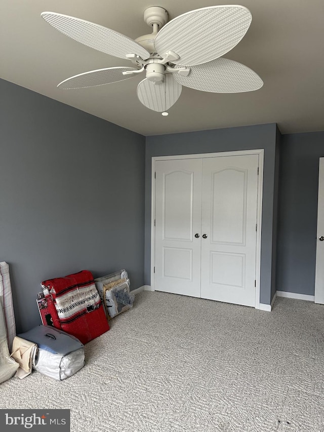 interior space with carpet floors, ceiling fan, and baseboards