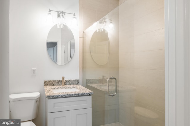 bathroom with a shower with door, vanity, and toilet