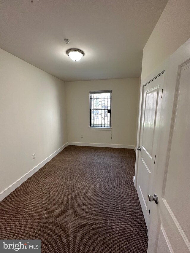 unfurnished room with dark colored carpet