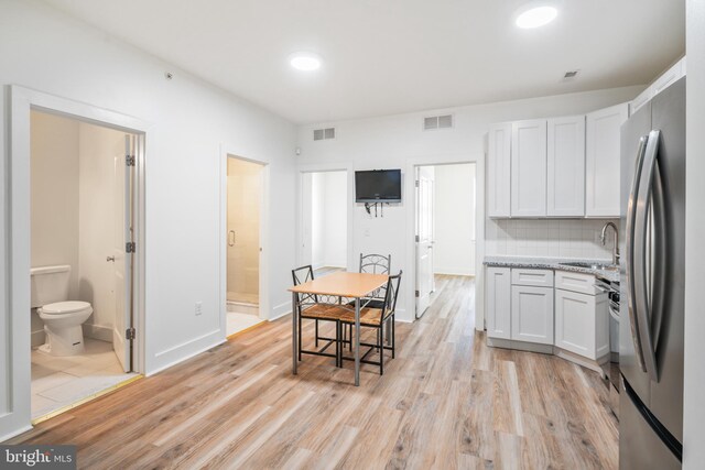 kitchen featuring white cabinets, light wood-type flooring, and stainless steel refrigerator