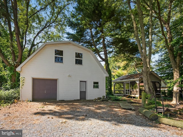 view of side of home featuring a garage and a gambrel roof