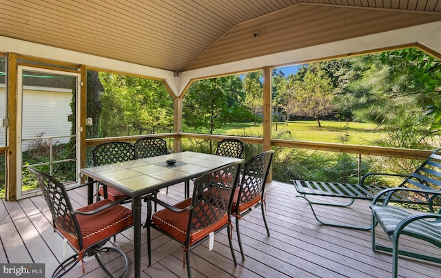 wooden deck featuring outdoor dining area and a lawn