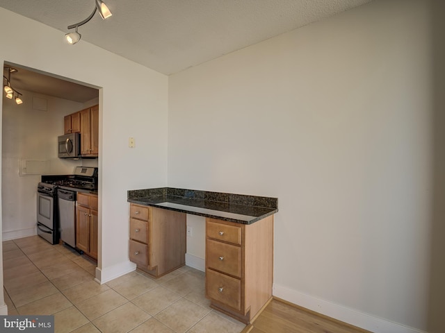 kitchen featuring a textured ceiling, stainless steel appliances, and light tile patterned floors