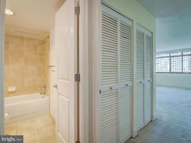 hallway featuring carpet floors, tile patterned flooring, and baseboards