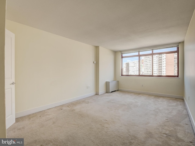 spare room with carpet floors, baseboards, and a textured ceiling