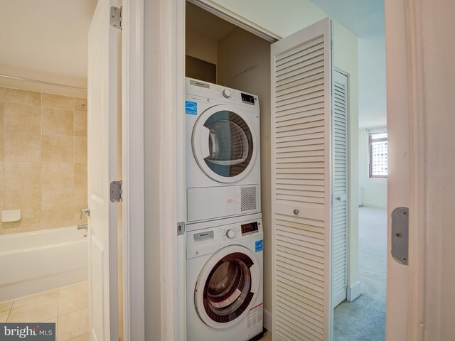 clothes washing area featuring light colored carpet and stacked washer / dryer