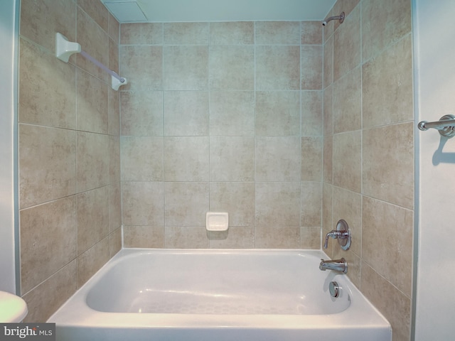 bathroom with toilet and tiled shower / bath combo