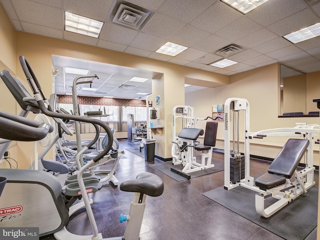 workout area with a drop ceiling, visible vents, and baseboards